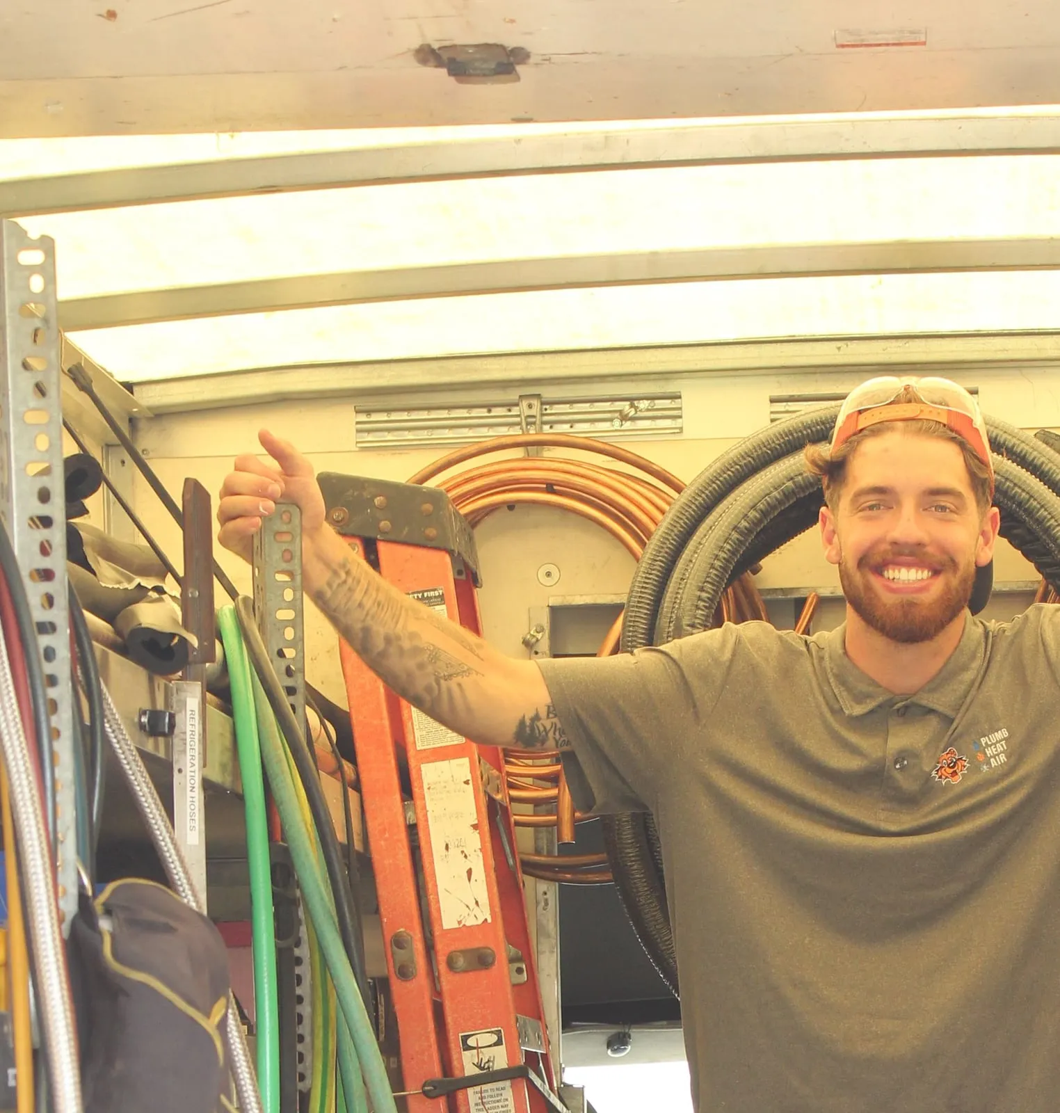 Smiling Tiger technician standing in the open back of a stocked service truck