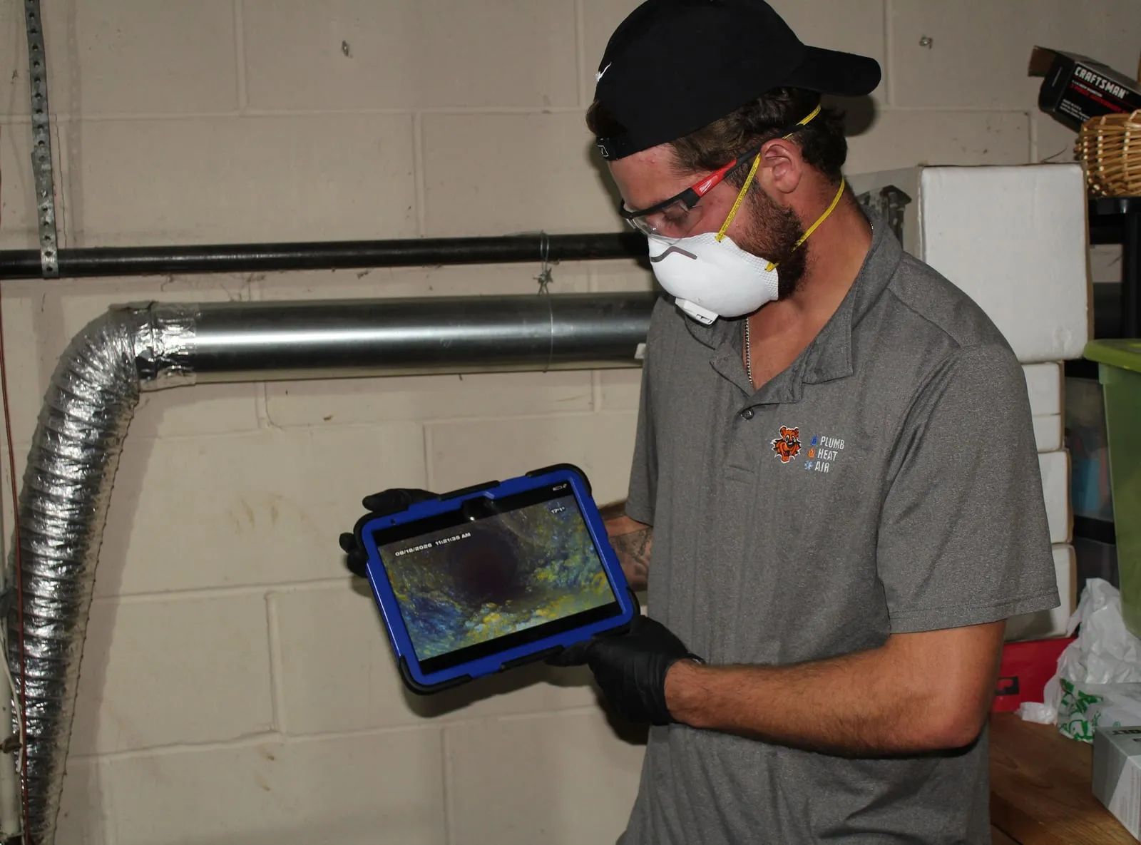 Tiger technician holding a tablet that shows camera footage from inside a pipe