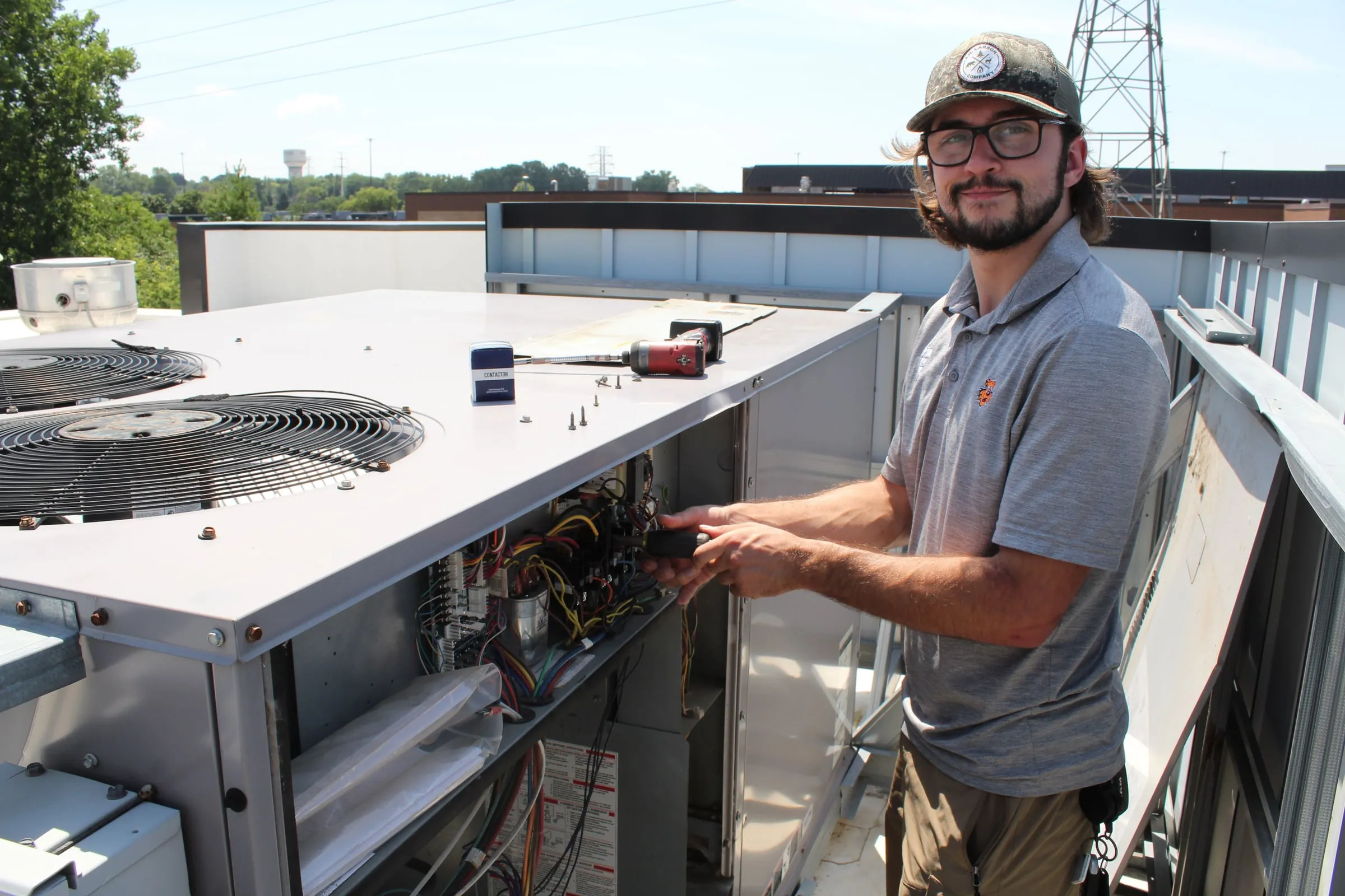 Smiling Tiger technician working in the control compartment of a commercial rooftop unit